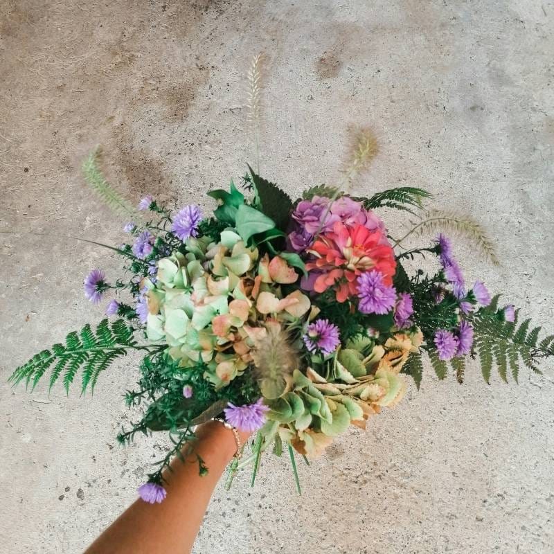 A Naples wedding florist holds a garden-style bouquet with a delicate hydrangea and hardy zinnias to showcase climate-smart floral options.