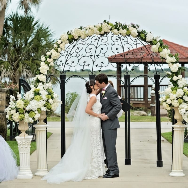 An elegant white floral arch with roses, illustrating the classic style and decor that a premier Naples wedding venue can accommodate.